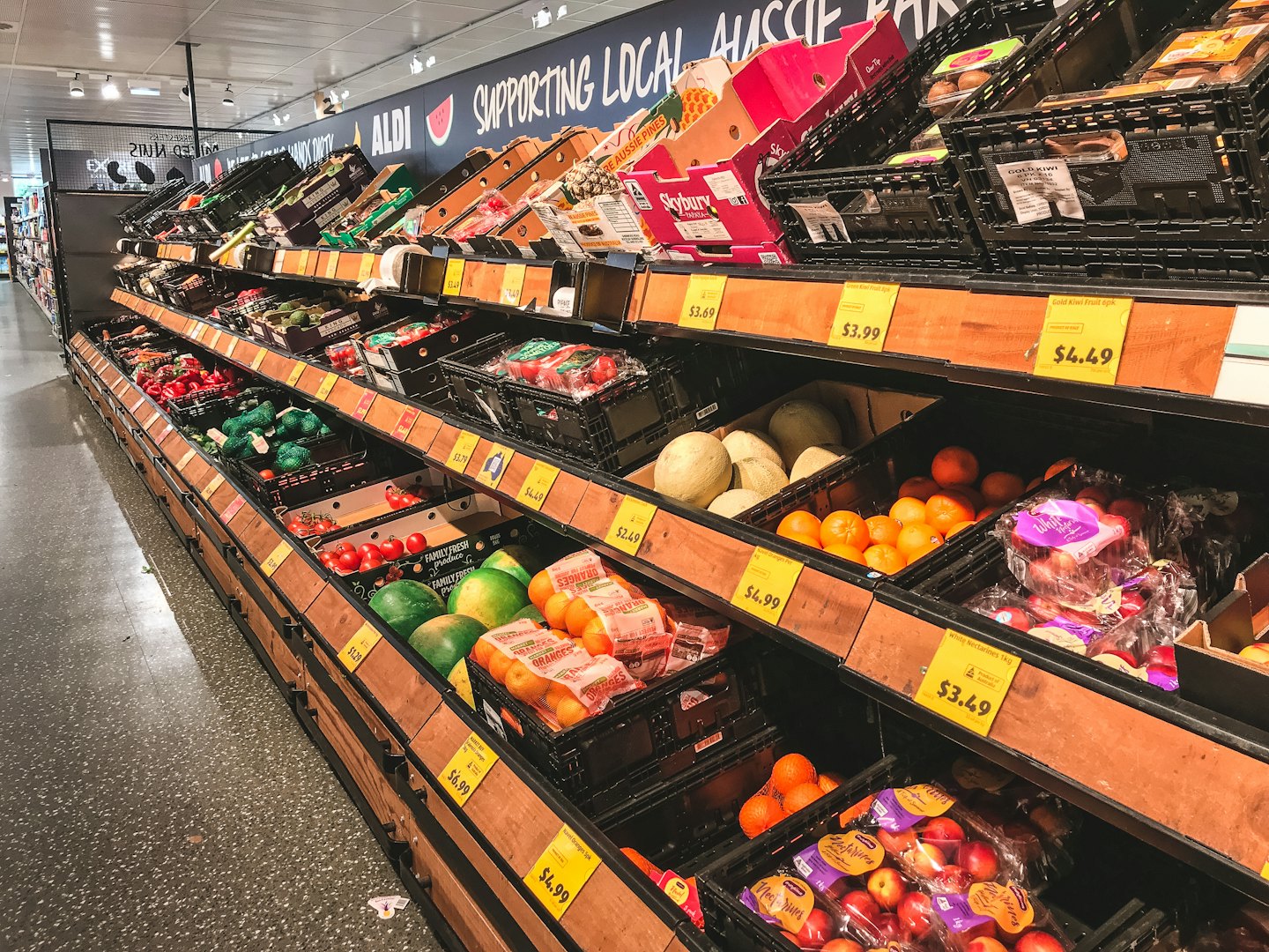 Bright supermarket aisle filled with fresh fruits and vegetables.
