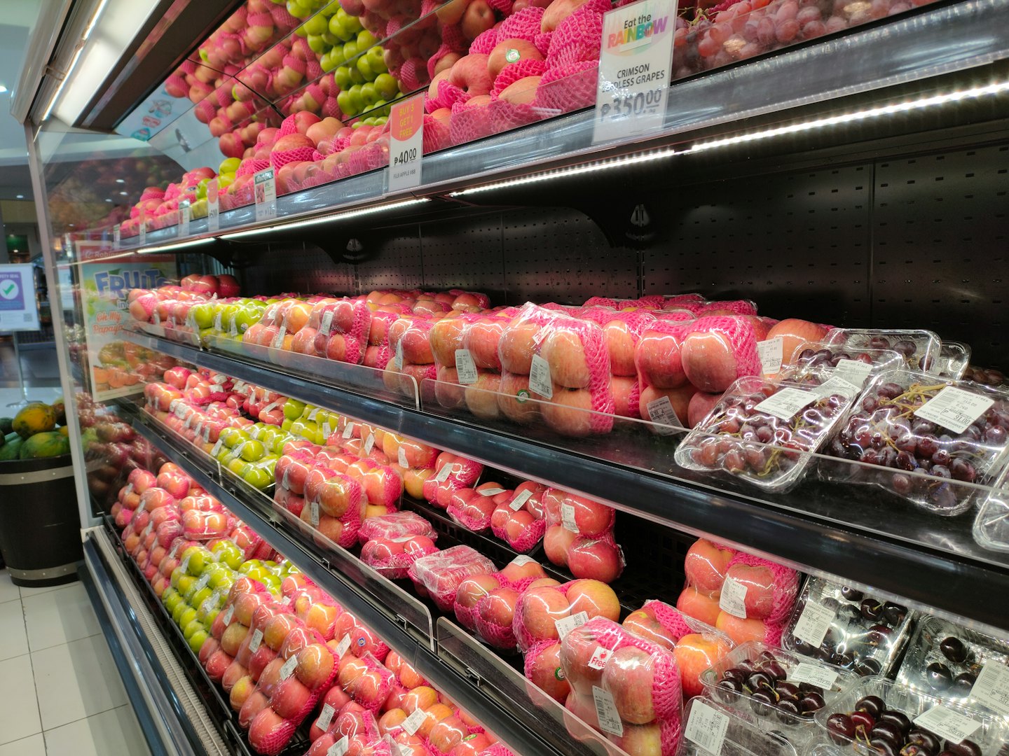 Neatly arranged apples and grapes in a supermarket produce section.