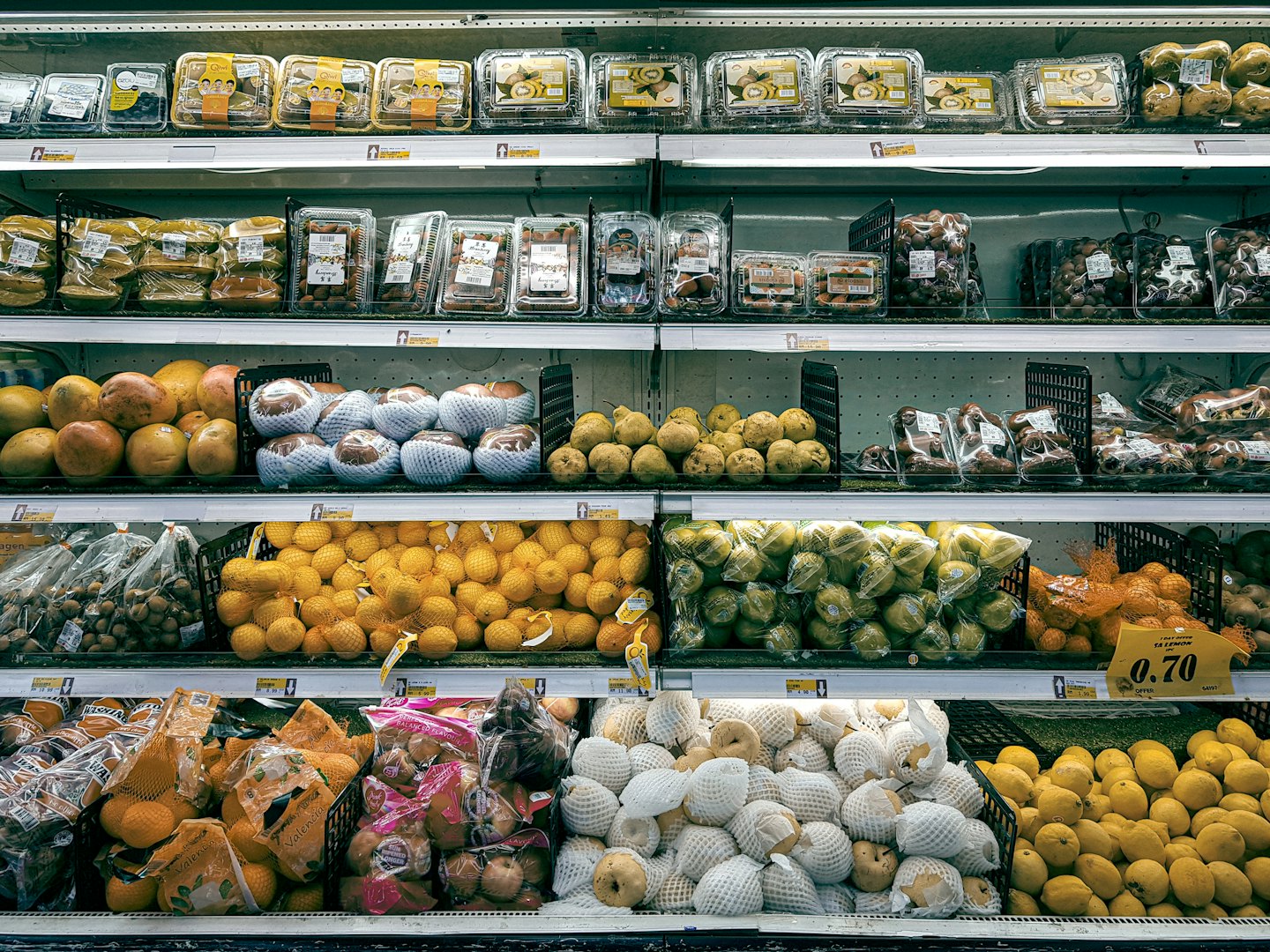 Refrigerated aisle stocked with fresh fruits and vegetables.